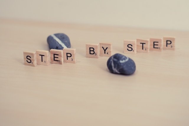Wooden blocks spell 'step by step'
